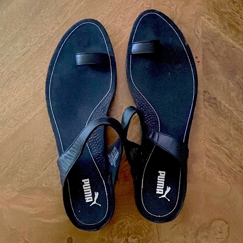 Puma black sandals with orange soles.